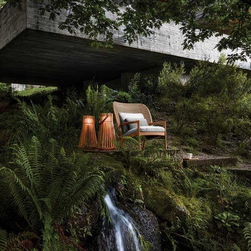 nature retreat: kay high-back lounge chair next to two gloster ambient ray outdoor lights