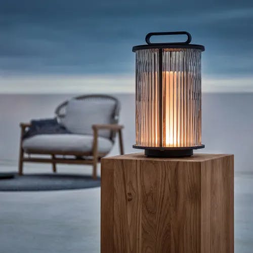 ambient small glass lantern on block table and fern low back lounge chair