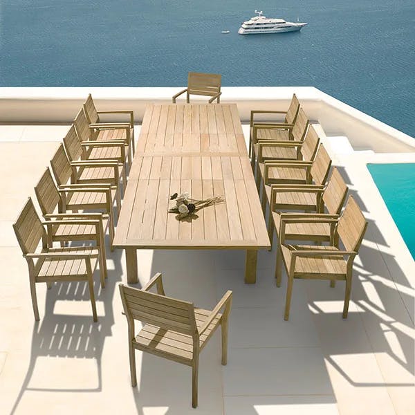barlow tyrie's apex 106-154" extending dining table staged with 14 horizon stacking armchairs (all in teak)