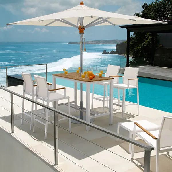 Four aura high-dining carver chairs staged with aura 55" high-dining table (arctic white aluminum frames