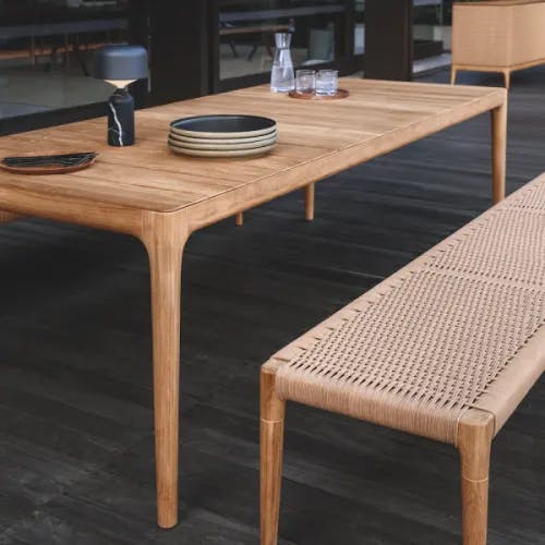 Close-up slatted teak table top and wheat wicker seat panel for dining bench (Courtesy of Gloster)
